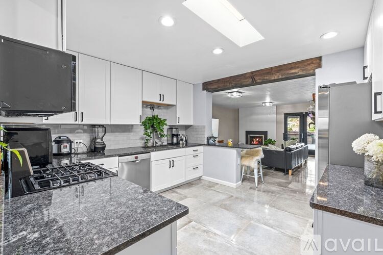 A modern kitchen with granite countertops and white cabinets.