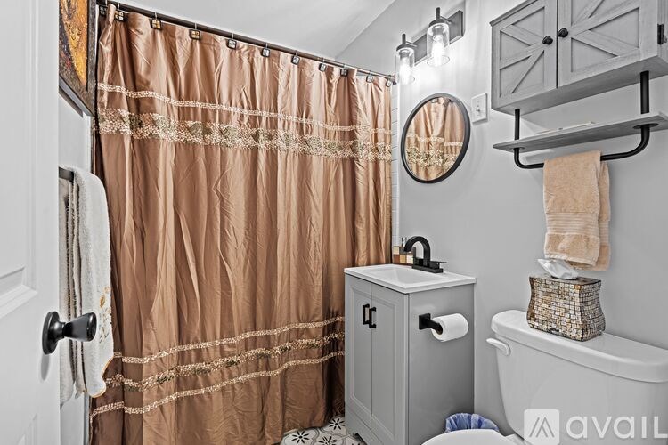 A bathroom with a brown shower curtain and a grey cabinet.