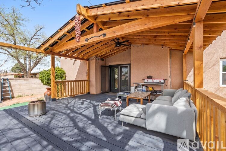 A wooden pergola over a patio with a grey couch and a table.