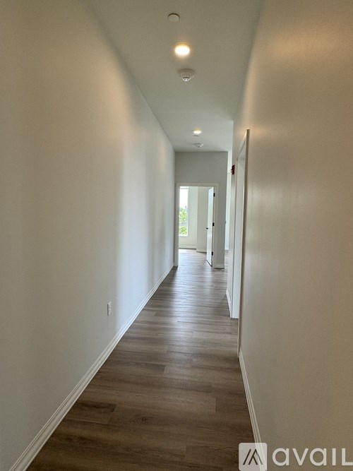 A long hallway with wood floors and white walls.