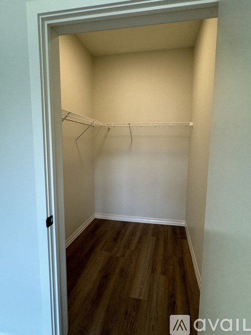 A small, empty room with a wooden floor and a white wall.