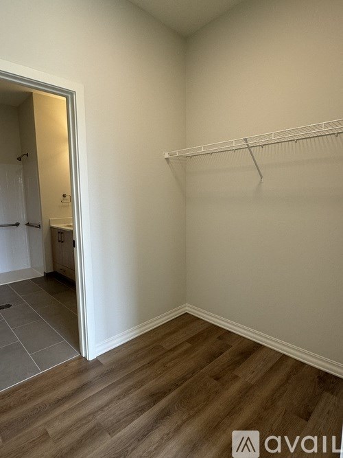 A room with a white wall and a wooden floor with a white shelf.
