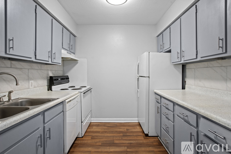 A kitchen with a white refrigerator, sink, and cabinets.