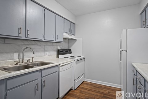 A kitchen with a white refrigerator, sink, and cabinets.
