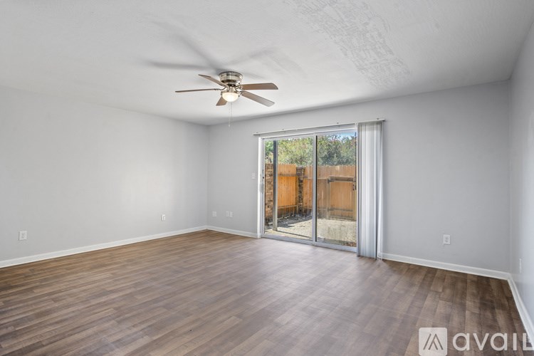 A room with a ceiling fan and sliding glass doors leading to a backyard.