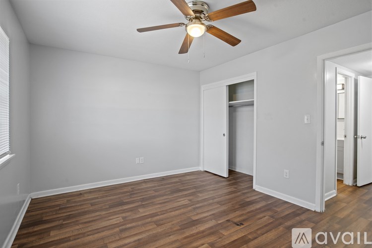 A room with a ceiling fan and wooden flooring.
