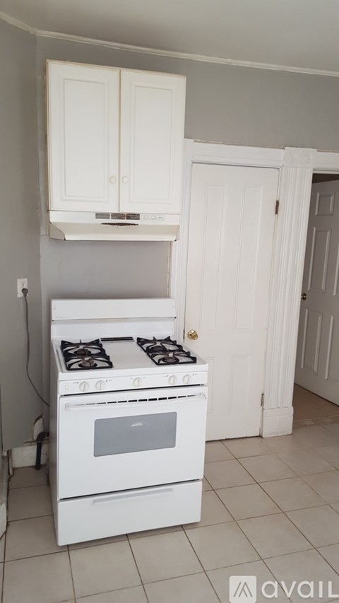 A white stove in a kitchen with white cabinets.