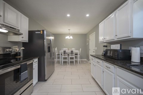 A kitchen with white cabinets and black appliances.