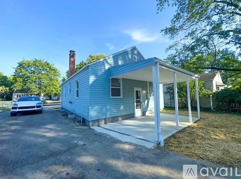 A blue house with a white porch and a car parked in front.