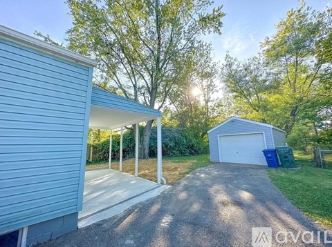 A blue house with a garage and a shed in the backyard.