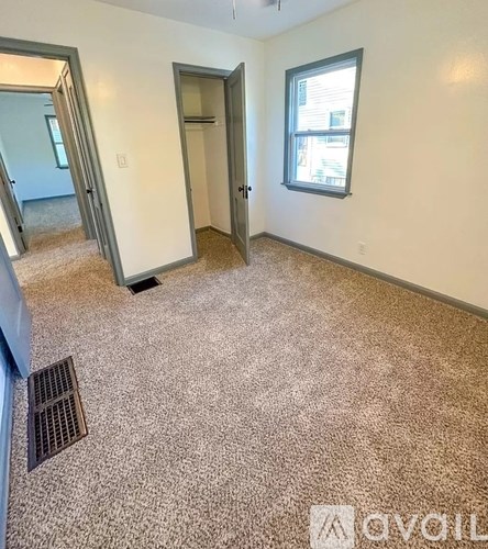 A room with a carpeted floor, a window, and a door.