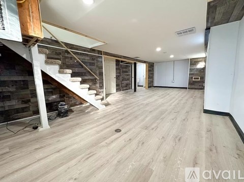 A spacious room with wooden flooring and a staircase with a wooden handrail.