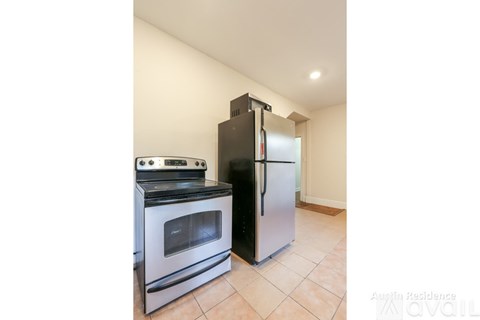 A black fridge and a silver oven in a kitchen.