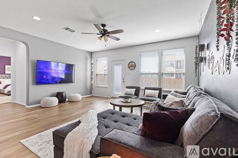 A modern living room with a grey sofa and a flat screen TV mounted on the wall.
