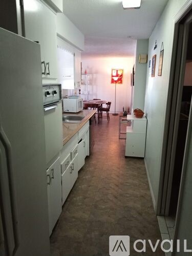 A kitchen with white appliances and a table with chairs.