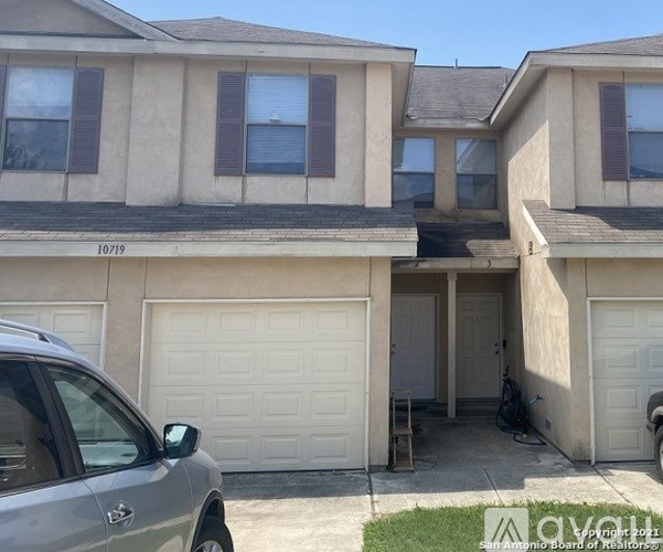 A two-story house with a garage and a car parked in front.
