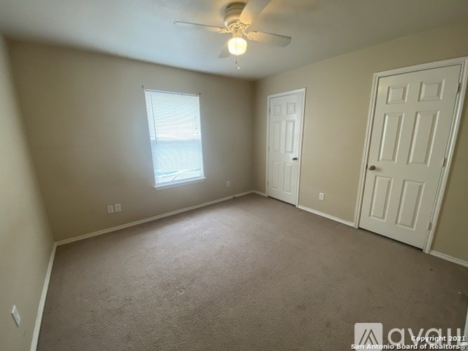 A room with a ceiling fan and two doors.