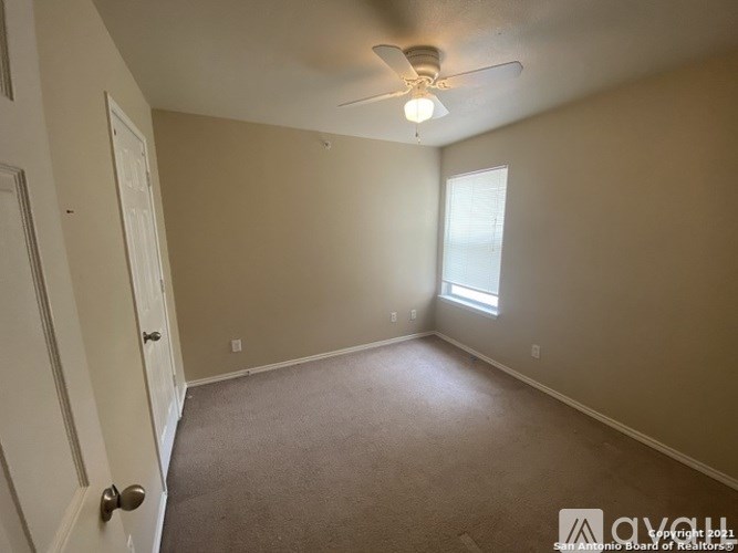 A room with a ceiling fan and a door.