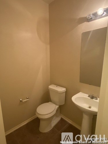 A small bathroom with a toilet, sink and mirror.