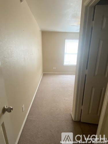 A hallway with a door on the right and a window on the wall.