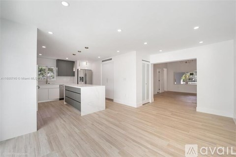 A spacious kitchen with white cabinets and a wooden floor.