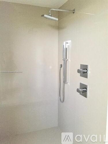A shower area with a glass door and a shower head.