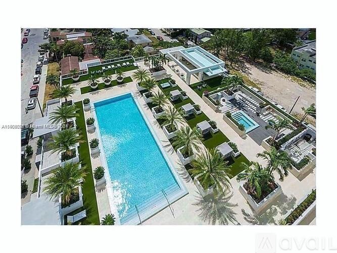 A large swimming pool surrounded by palm trees and a building with a glass facade.