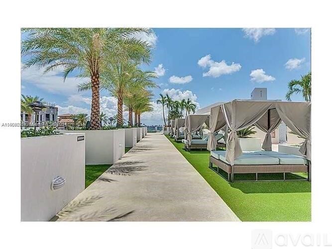 A row of white beach huts are lined up on a concrete path.