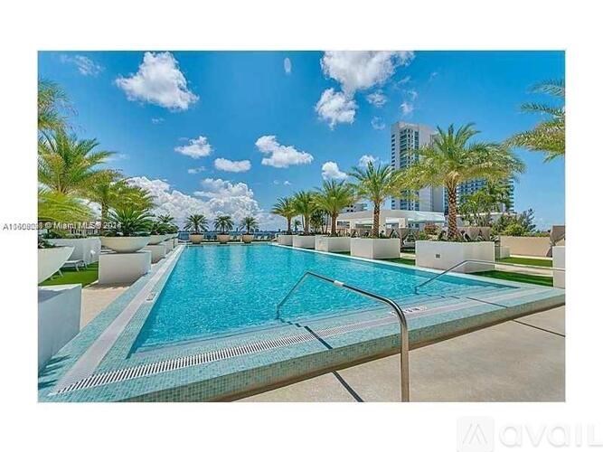 A large swimming pool surrounded by palm trees and modern buildings.
