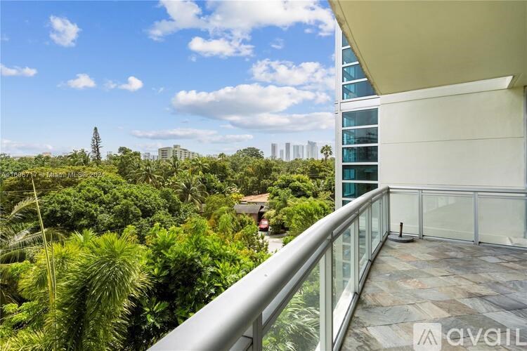 A balcony overlooks a lush green landscape with a city skyline in the distance.