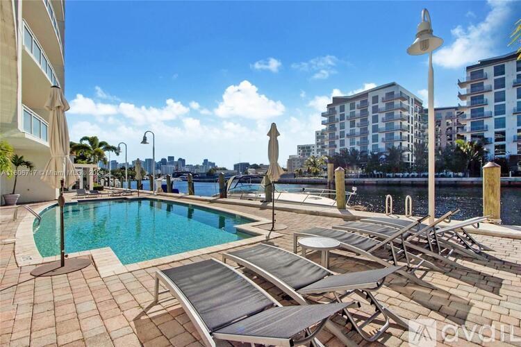 A pool area with sun loungers and a view of the city.