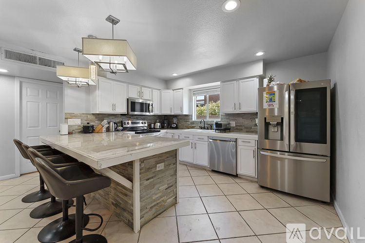 A modern kitchen with a center island and stainless steel appliances.