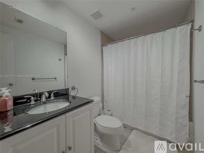 A bathroom with a toilet, sink, and shower curtain.