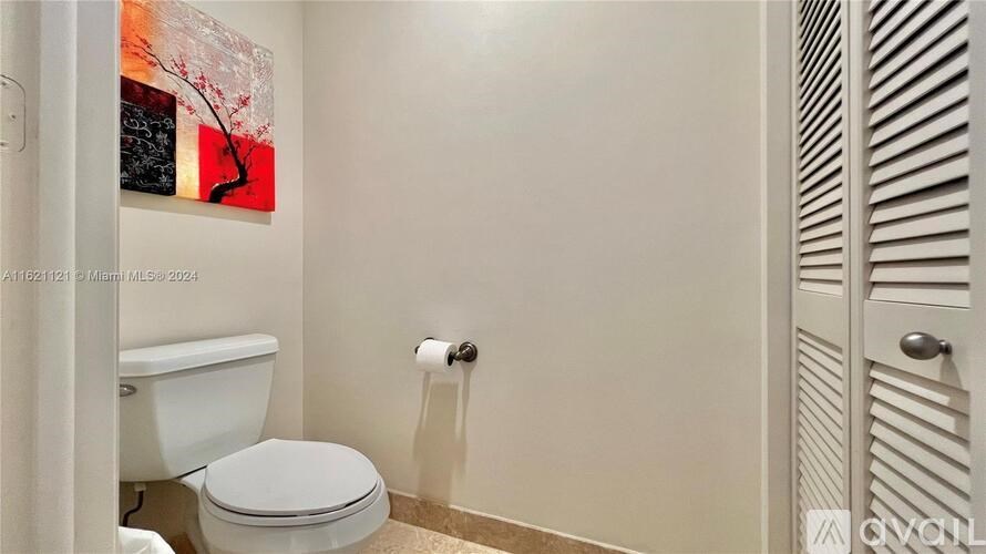 A white toilet in a bathroom with a painting on the wall.