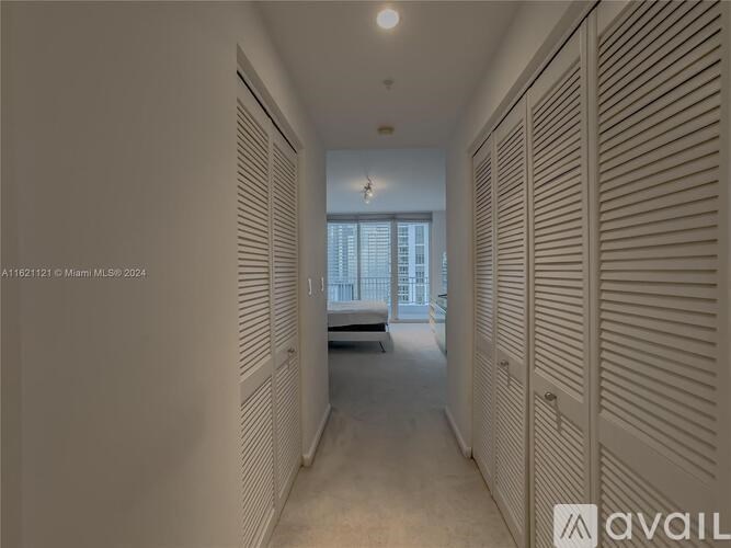 A long hallway with a bench and a window at the end.