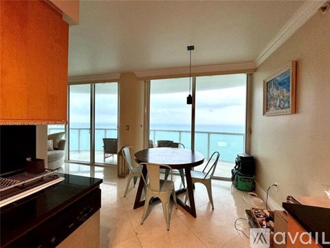 A living room with a table and chairs and a view of the ocean.