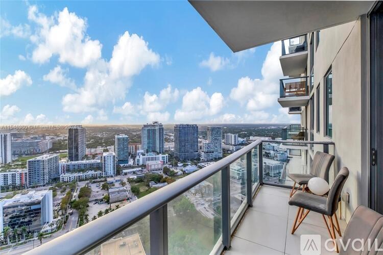 A balcony with chairs overlooks a cityscape.