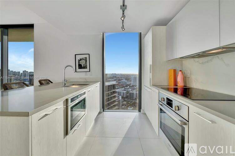 A kitchen with white cabinets and a view of the city.