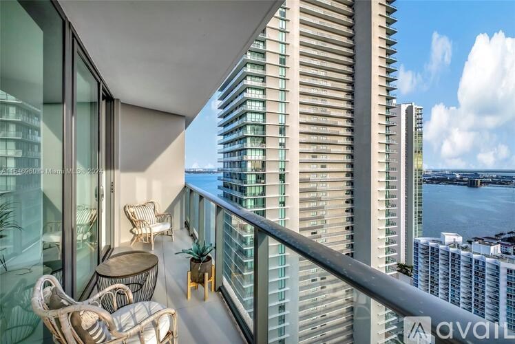 A balcony with chairs and a table overlooks a body of water.