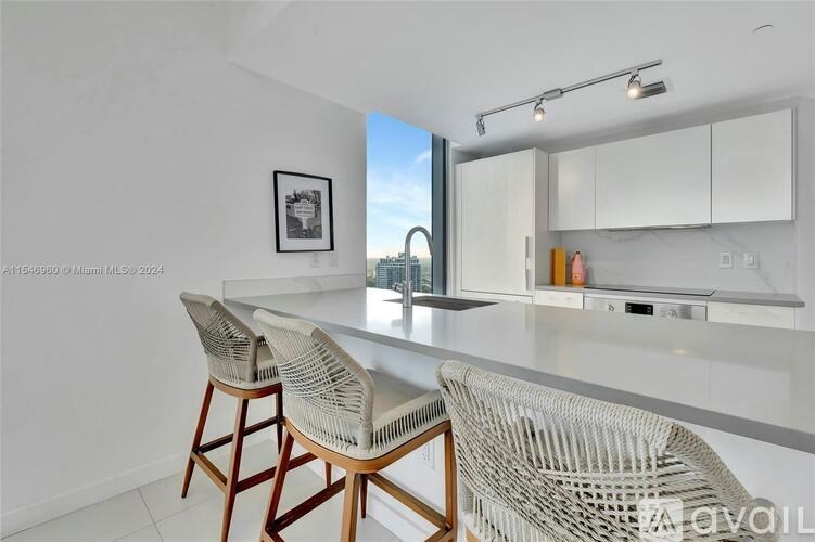 A kitchen with white cabinets and a framed picture on the wall.