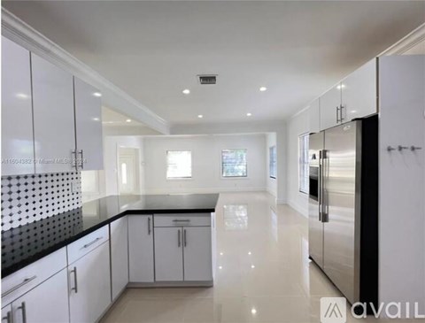 A modern kitchen with white cabinets and a black countertop.