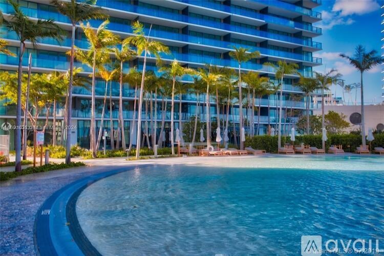 A large pool in front of a building with palm trees.