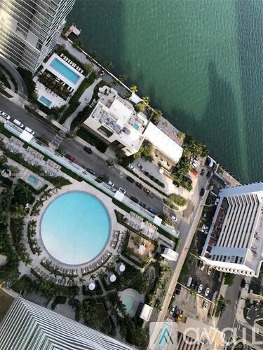 A large round pool is surrounded by a building and a road.
