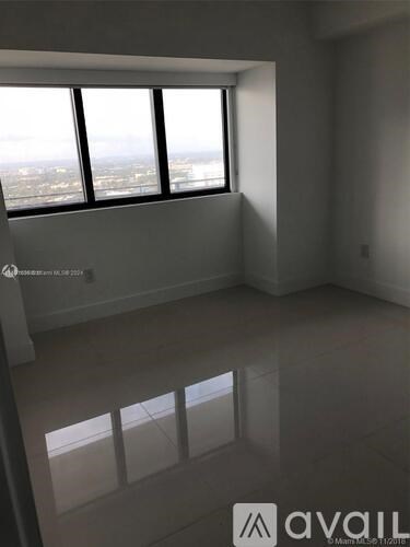 A large empty room with a view of the city through the windows.