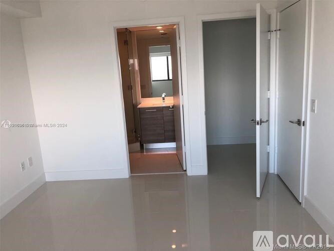 A room with a white wall and a wooden door leading to another room.