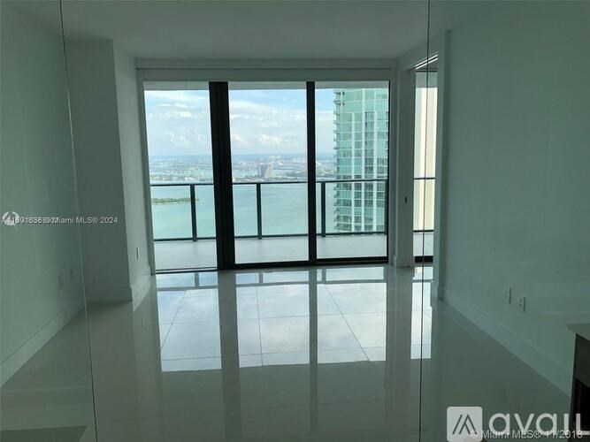 A large, empty room with a view of the city through floor-to-ceiling windows.