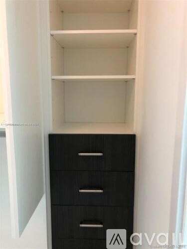 A black drawer cabinet with three drawers is open.