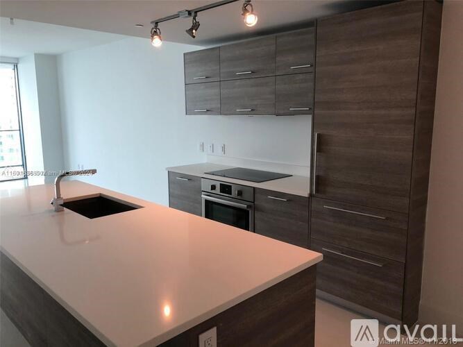 A modern kitchen with a white countertop and dark wood cabinets.