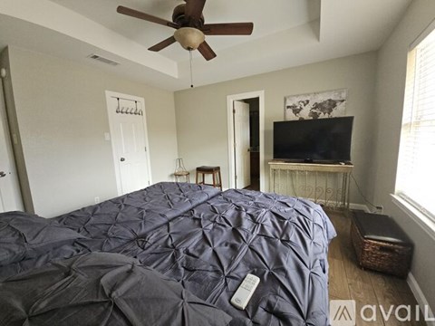 A bedroom with a bed covered in a blue comforter and a ceiling fan.