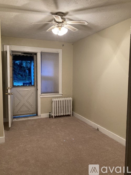 A room with a ceiling fan and a window with a view of trees outside.